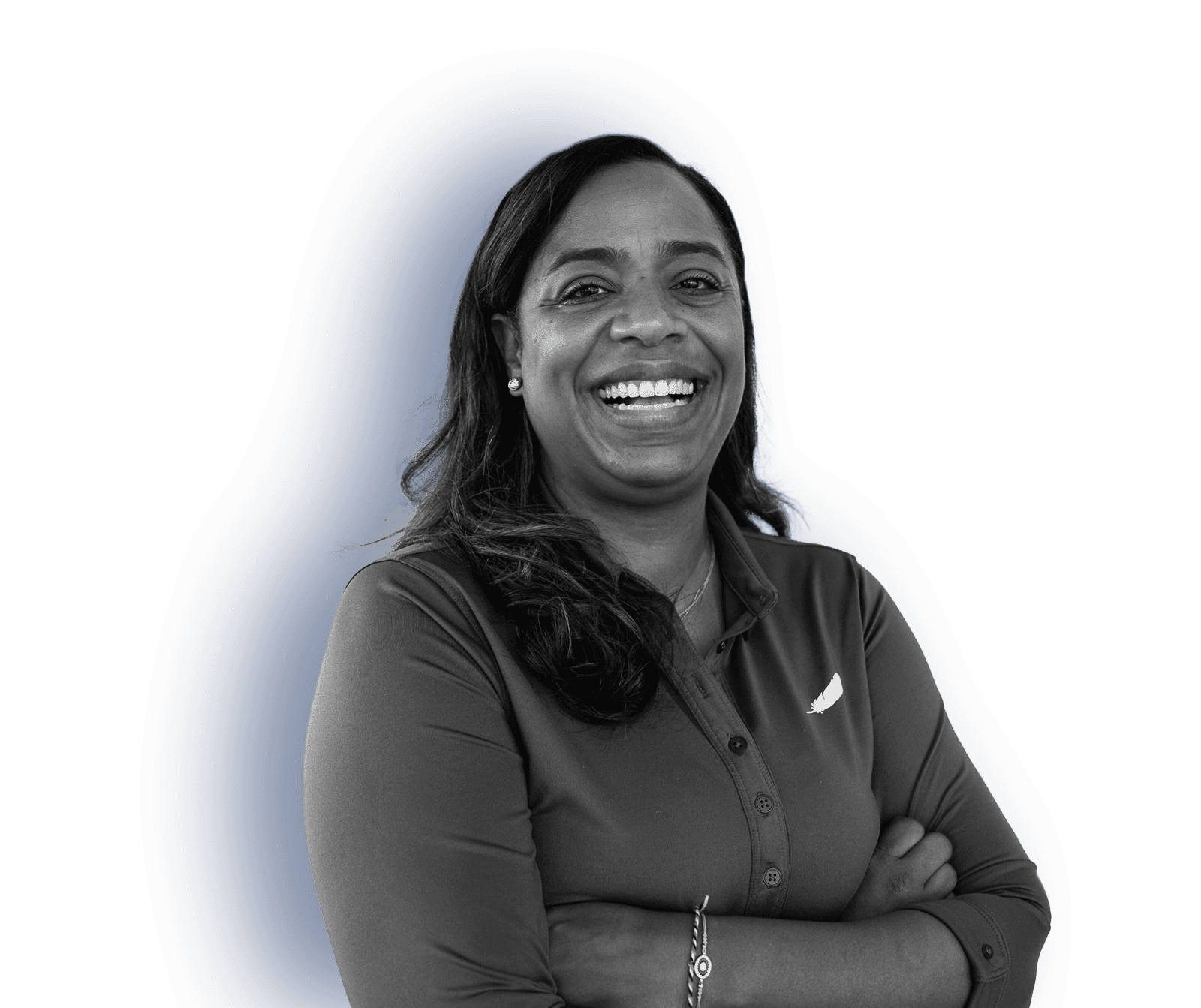 A woman with a big smile stands with her arms crossed. She’s wearing a button-down Blue Origin branded shirt.