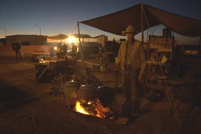 Blue Origin employees and guests cook food over a fire before watching the Goddard launch.