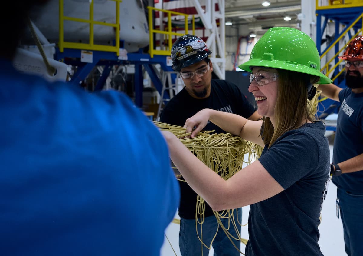 A woman with the look of excitement as she and three others work on the manufacturing floor