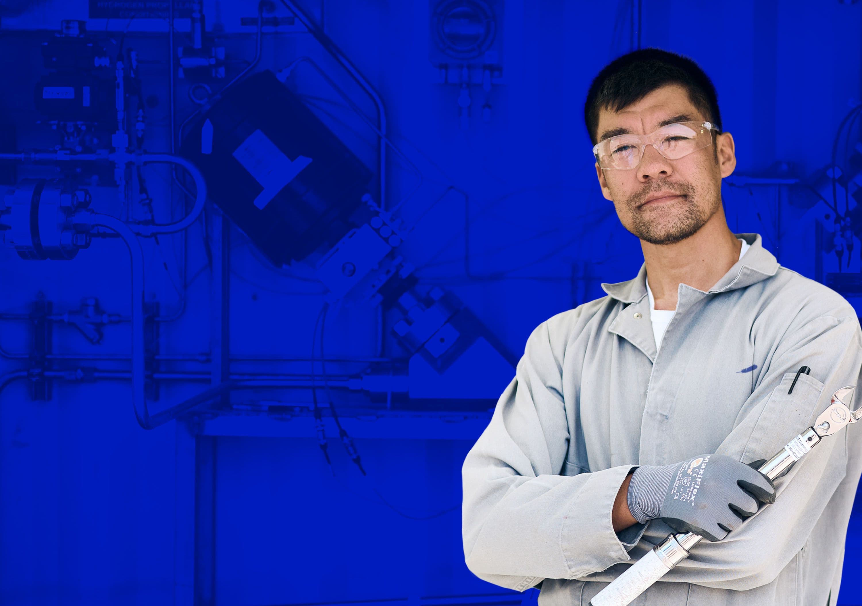 A man in a collared shirt holding a wrench with gloves