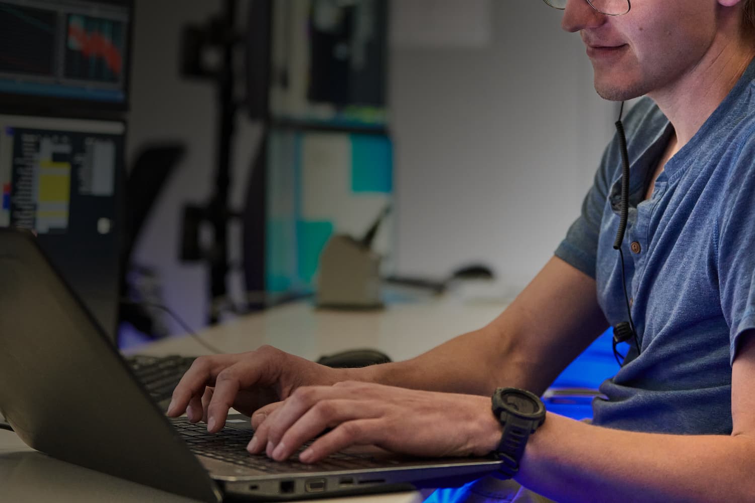 An employee’s hands and torso are visible as they sit at a desk, typing on a laptop.