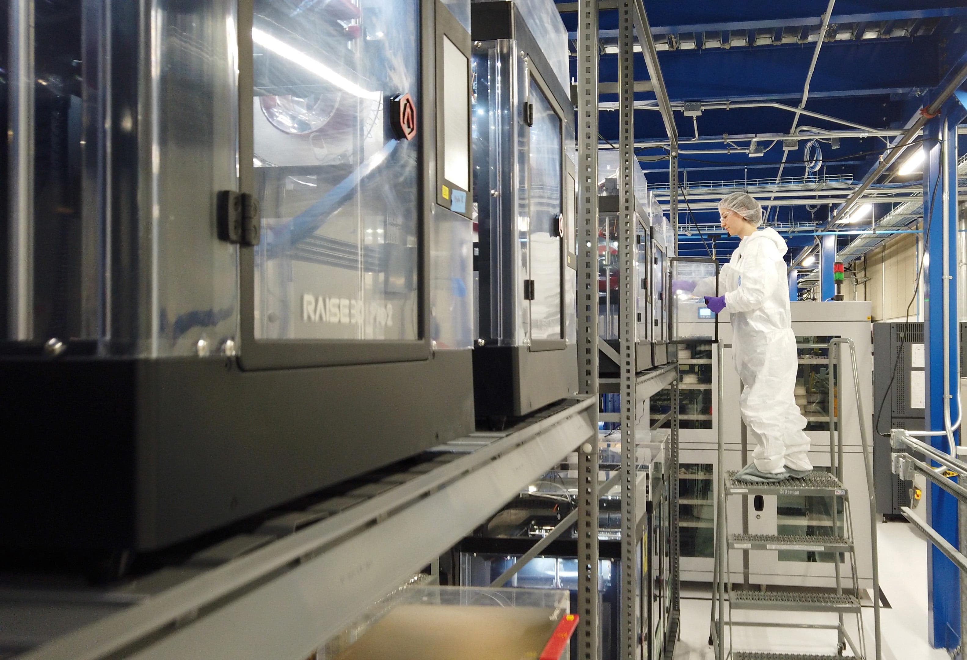 A Blue Origin employee stands in front of a machine used to 3D print face shields during the COVID-19 pandemic.