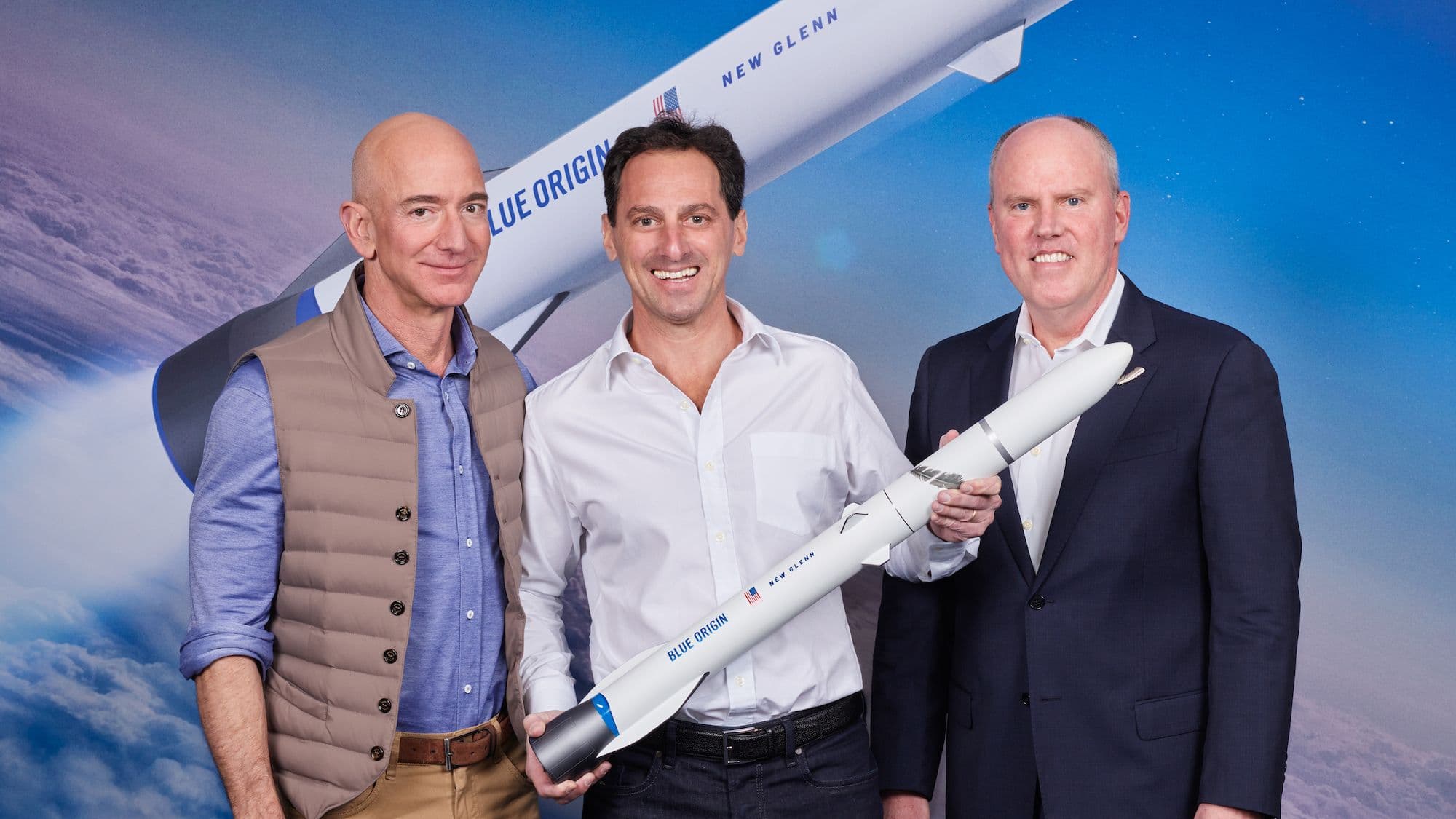 Blue Origin Founder Jeff Bezos and CEO Bob Smith pose with a customer holding a model of New Glenn.