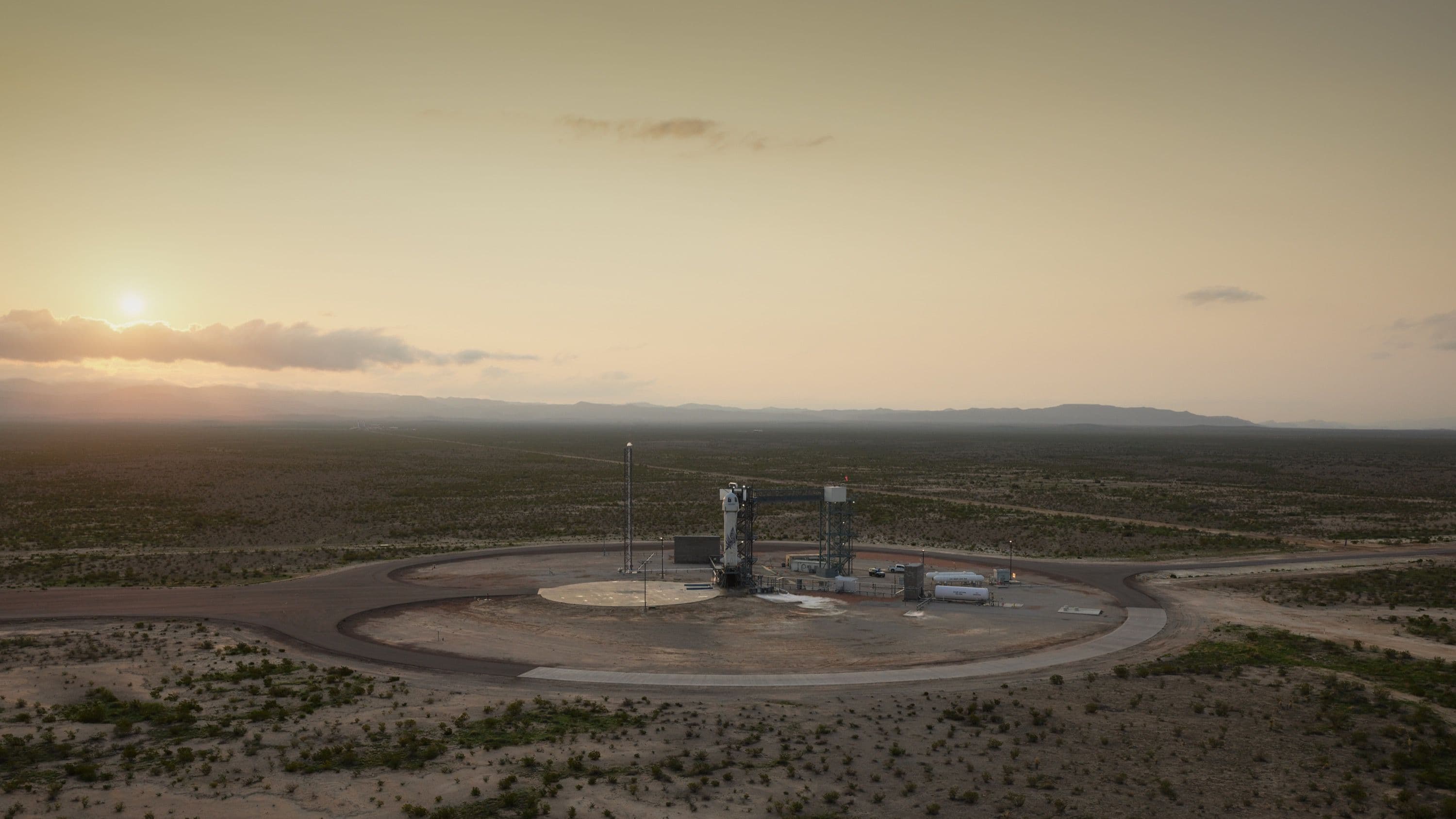 New Shepard on the launch pad at sunrise with the West Texas desert in the background.