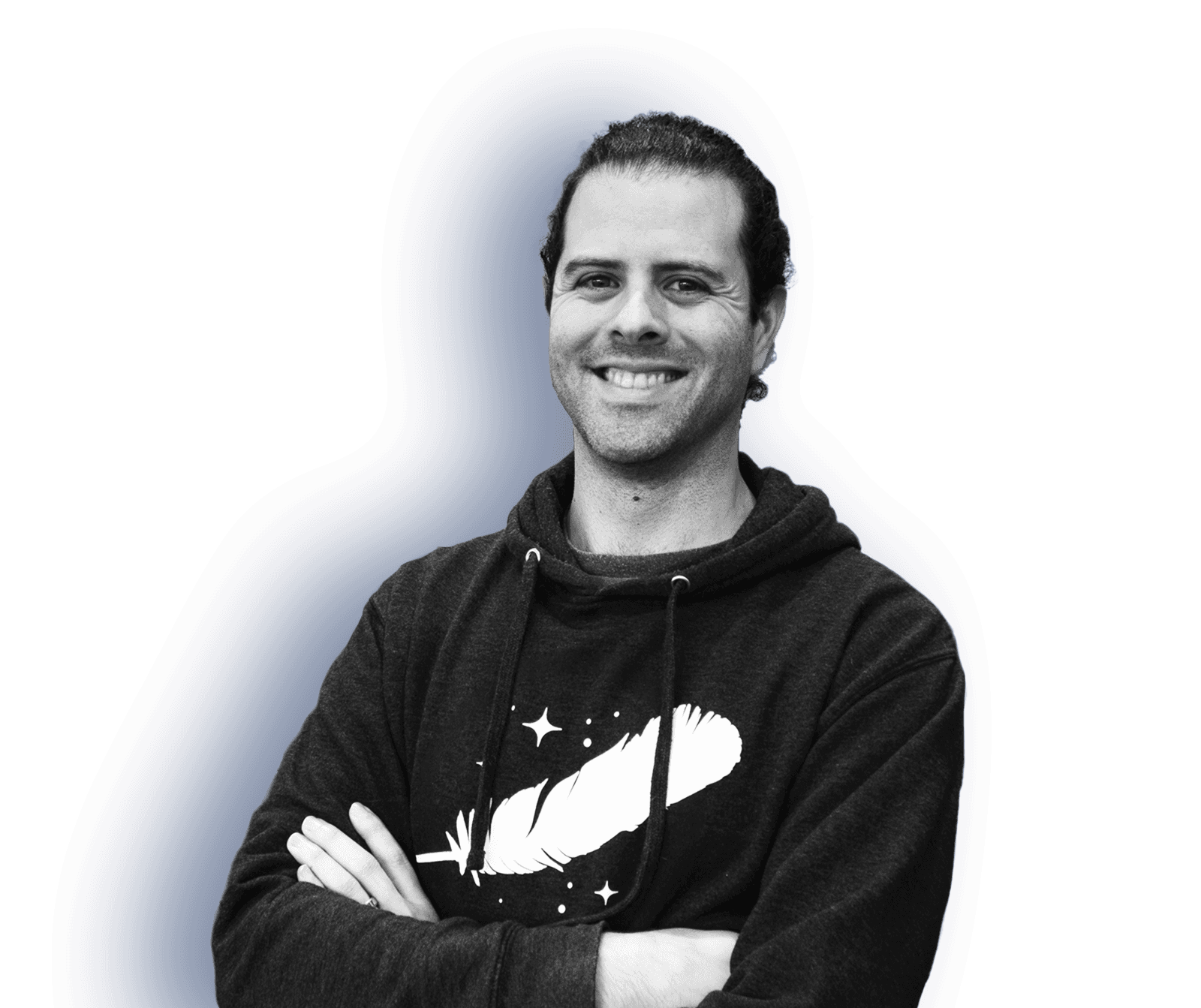 A man with hair pulled back stands with his arms crossed, smiling, in a hoodie with the Blue Origin feather logo.
