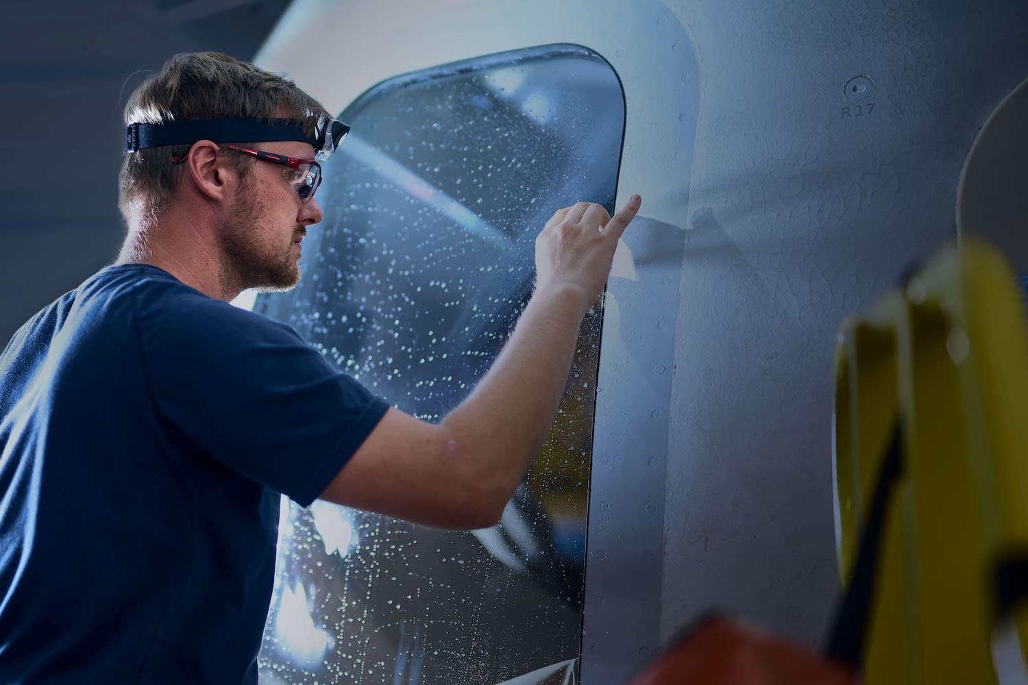 A Blue Origin employee wearing a t-shirt, headlamp, and safety glasses.